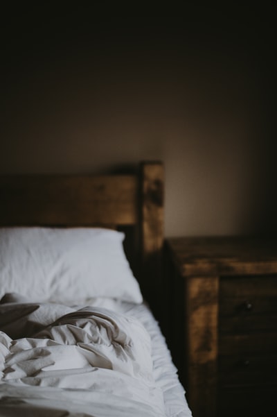 棕色木制床头柜旁的白色床垫